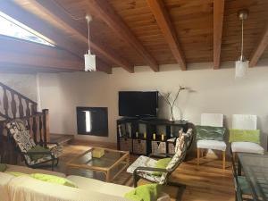 ein Wohnzimmer mit einem Sofa und einem TV in der Unterkunft Ático aires de gredos in Candeleda