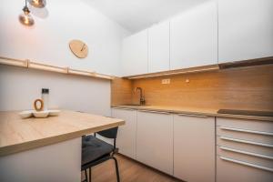 uma cozinha com armários brancos e uma mesa de madeira em City Center Apartment - Modern & Elegant em Bratislava