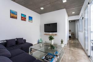 sala de estar con sofá azul y TV en Casa volcán de caldera blanca en Tinguatón