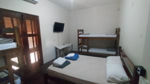 a small room with two beds and a television at Espaço Viagi Hostel in Taubaté