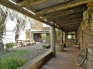 eine Holzterrasse mit Bänken und ein Steingebäude in der Unterkunft Valle del Hilo de la Vida in Minas