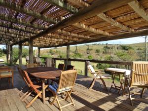 eine Holzterrasse mit einem Holztisch und Stühlen in der Unterkunft Valle del Hilo de la Vida in Minas