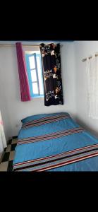 a bedroom with a bed with blue sheets and a window at Chez Housna in Rabat