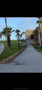 eine Straße mit Palmen in einem Park mit einem Gebäude in der Unterkunft Chez Housna in Rabat