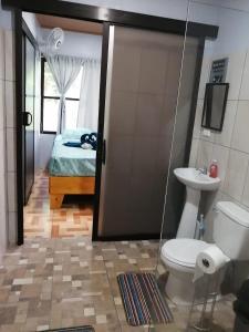 a bathroom with a toilet and a sink and a bed at Villas Cacao in Fortuna