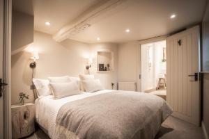 um quarto com uma grande cama branca com almofadas brancas em The Three Horseshoes em Burford