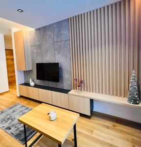a living room with a table and a television at Apartment 202 - Aparthotel Zlatni Javor in Jahorina