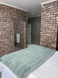 a bedroom with a bed with a brick wall at Vintage Corner Accomodation in Walvis Bay