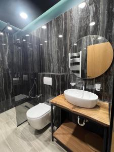 a bathroom with a sink and a toilet and a mirror at B.G Luxury Suites in Korçë