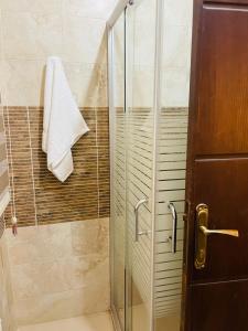 a shower with a glass door and a towel at تلاع العلي in Amman