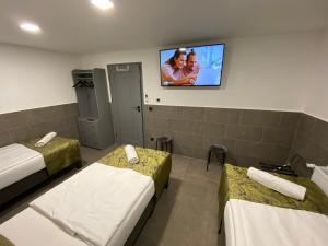 a room with two beds and a tv on the wall at Levendula Vendégház in Győr