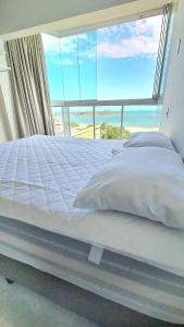 a bedroom with a large bed with a large window at Cobertura Duplex Vista Mar Meaipe in Guarapari