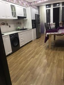 a kitchen with white cabinets and a wooden floor at Ahmedli in Baku
