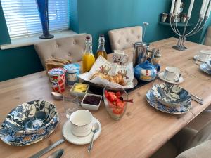 a wooden table with breakfast foods and drinks on it at 2 Friends Close in Kent