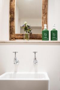 - un lavabo avec 2 bouteilles de savon et un miroir dans l'établissement The Three Horseshoes, à Burford