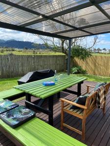 een groene picknicktafel en stoelen onder een pergola bij Relax Cabin - Waihi Beach Holiday Home in Waihi Beach