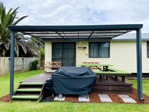 een paviljoen met een picknicktafel, een bank en een huis bij Relax Cabin - Waihi Beach Holiday Home in Waihi Beach