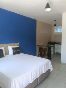 um quarto com uma cama branca e uma parede azul em Flats 1 Locação Penedo RJ em Penedo