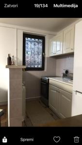 uma cozinha com armários brancos e uma janela em Milja Goč em Kraljevo