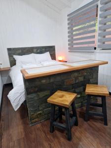 a bed and two stools in a room with a desk at Ecos del Manantial in Villarrica