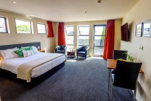 um quarto com uma cama, uma secretária e cadeiras em Coleraine Suites & Apartments em Greymouth