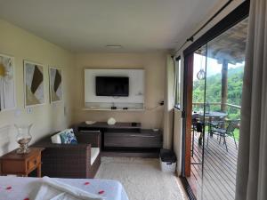 um quarto com uma cama, uma televisão e uma varanda em Cantinho do marinheiro em Paraty