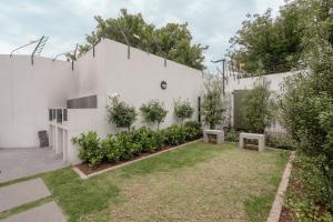 a garden with two benches in front of a white building at Tranquil Zen Oasis in Midrand: The Perfect Retreat in Midrand