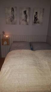 een bed in een slaapkamer met foto's aan de muur bij Cozy apartment close to nature, Kvaloya. in Kvaløya