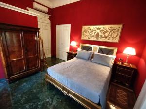 1 dormitorio con paredes rojas y 1 cama con 2 lámparas en NOBILI LIBARDI - VILLA BASEVI, en Verona
