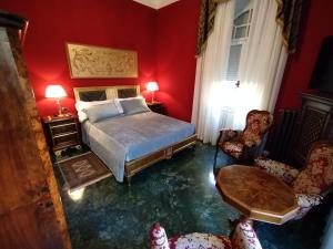 1 dormitorio con paredes rojas, 1 cama y 2 sillas en NOBILI LIBARDI - VILLA BASEVI, en Verona