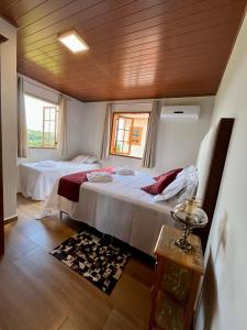 a bedroom with two beds and a wooden ceiling at Casa 2 Chalé Alto dos Bandeirantes-Tiradentes in Tiradentes