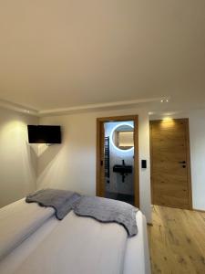 - une chambre avec un lit blanc et un miroir dans l'établissement DAS MANFRED, à Sankt Michael im Lungau