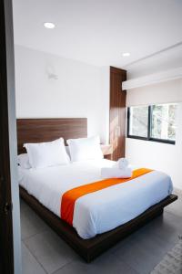 Monyxbnb Hotel في بويرتو فايارتا: غرفة نوم بسرير كبير وملاءات بيضاء برتقالية