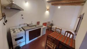 a kitchen with a stove and a sink and some chairs at Cabañas Tierra Andina in Tilcara
