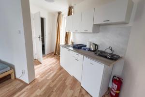 a kitchen with white cabinets and a wooden floor at Apartments Gala Abertamy in Abertamy