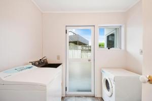 eine weiße Waschküche mit Waschmaschine und Trockner in der Unterkunft The White House - Taupo Holiday Home in Taupo