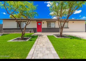 two trees in front of a house with a red door at La casa de Reymar in Phoenix