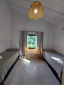 a room with two beds and a window and a chandelier at Al pie del Cerro in Villa La Angostura