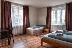 a bedroom with two beds and a desk and windows at Apartments Gala Abertamy in Abertamy
