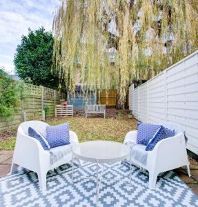 un patio con 2 sillas, una mesa y un árbol en 4 Bedroom, large house, with private parking and just 23 minute train ride to Waterloo, en Raynes Park
