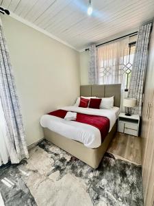 een slaapkamer met een groot bed met rode kussens bij 3 BDR Luxurious Villa in Milimani Kisumu in Kisumu