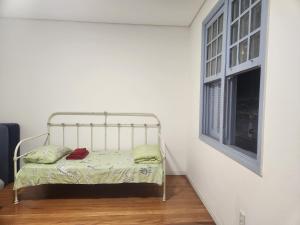 Cama pequeña en habitación con ventana en Casa Ipê Baobá en São Paulo