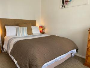1 dormitorio con 1 cama grande con manta marrón en Wee Blue BnB- Central Cosy Villa, en Timaru