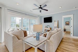 a living room with a couch and a ceiling fan at Of Course You Can in Holden Beach
