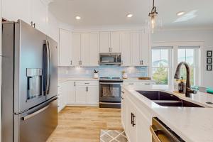 a kitchen with white cabinets and a stainless steel refrigerator at Of Course You Can in Holden Beach