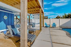 a patio with chairs and a swimming pool at Of Course You Can in Holden Beach