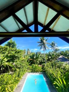 a person sitting in a swimming pool in a resort at Tropical Jungle Villa 5 min walk to Cloud 9 in General Luna