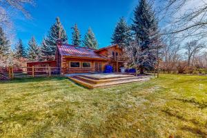 a log cabin with a deck and a yard at Sawtooth Serenity in Hailey