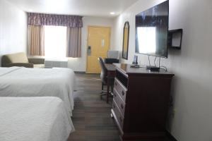 ein Hotelzimmer mit 2 Betten, einem Schreibtisch und einem Spiegel in der Unterkunft Rodeway Inn Tucumcari in Tucumcari