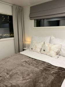 um quarto com uma cama com almofadas brancas e uma janela em Arctic Circle Guesthouse em Rovaniemi